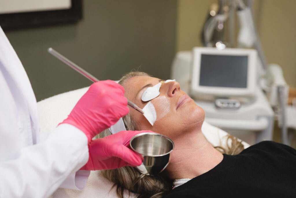 A patient at The Skin Clinic is having a custom facial applied gently by a provider with a wide-flared, white brush. Custom facials like these are a great addition to anyone's skin care in Mankato routine.